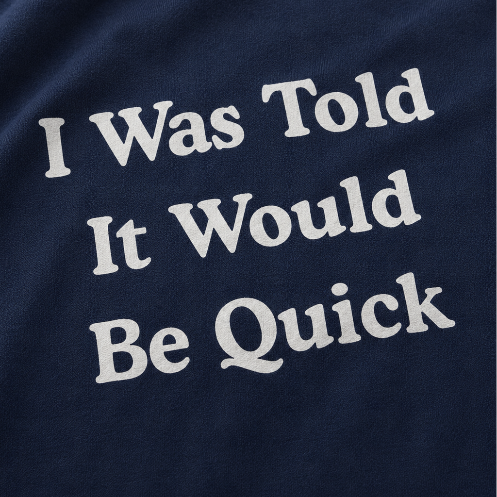 Close-up of a navy blue fabric surface with large white text reading 'I Was Told It Would Be Quick'.