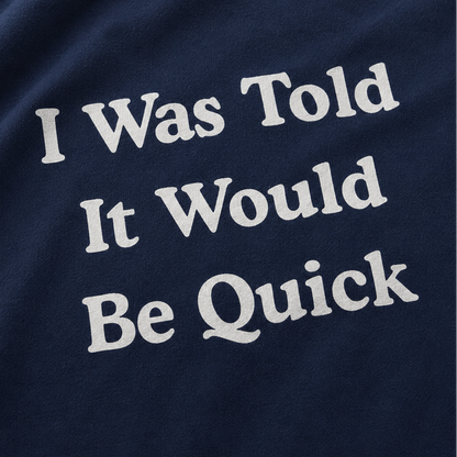 Close-up of a navy blue fabric surface with large white text reading 'I Was Told It Would Be Quick'.