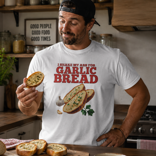 Man in a kitchen wearing a t-shirt with garlic bread graphic and text, holding garlic bread.