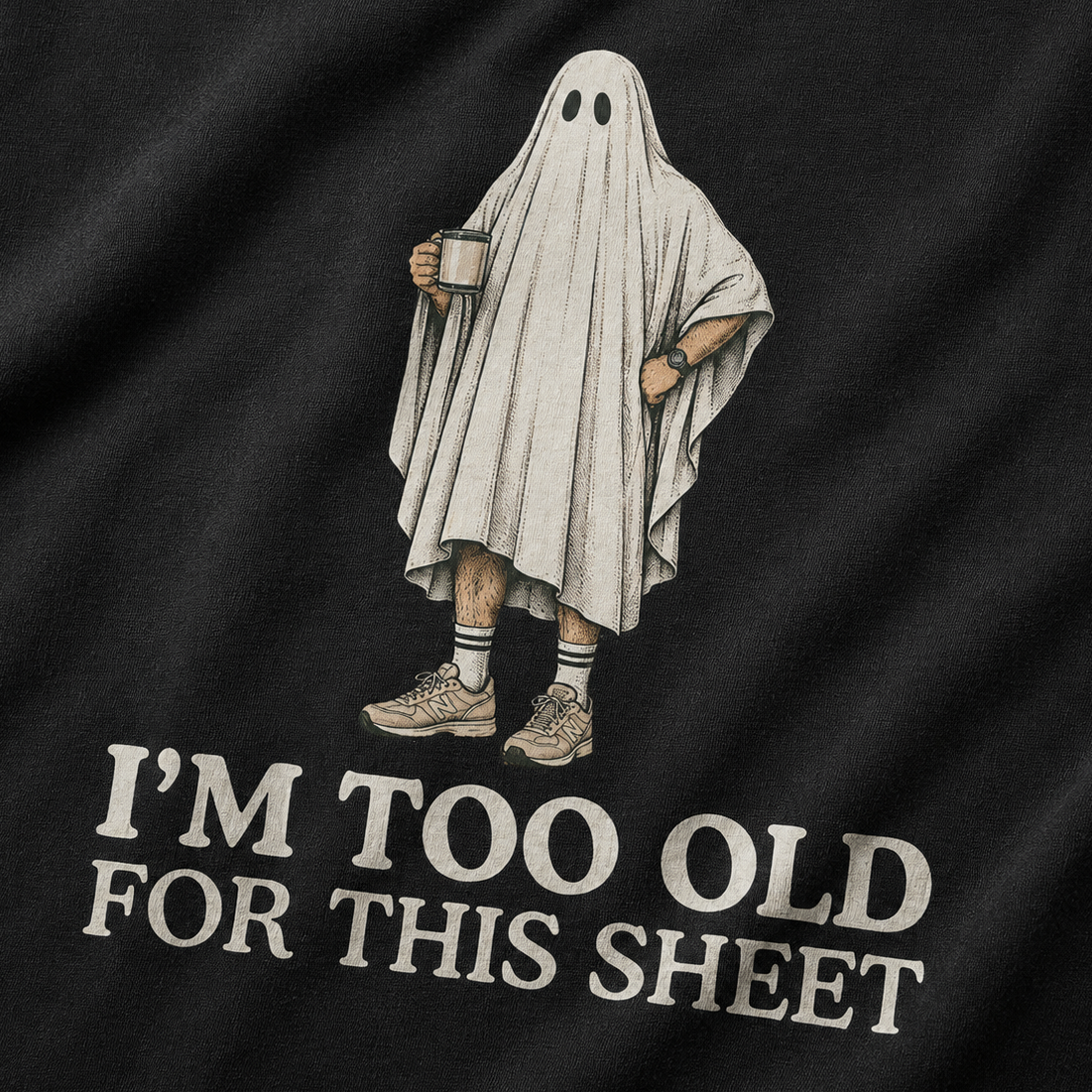 Close-up of a black T-shirt with a printed graphic of a person in a ghost sheet holding a mug, with the text 'I'M TOO OLD FOR THIS SHEET' below.