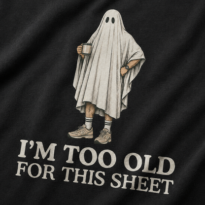 Close-up of a black T-shirt with a printed graphic of a person in a ghost sheet holding a mug, with the text 'I'M TOO OLD FOR THIS SHEET' below.