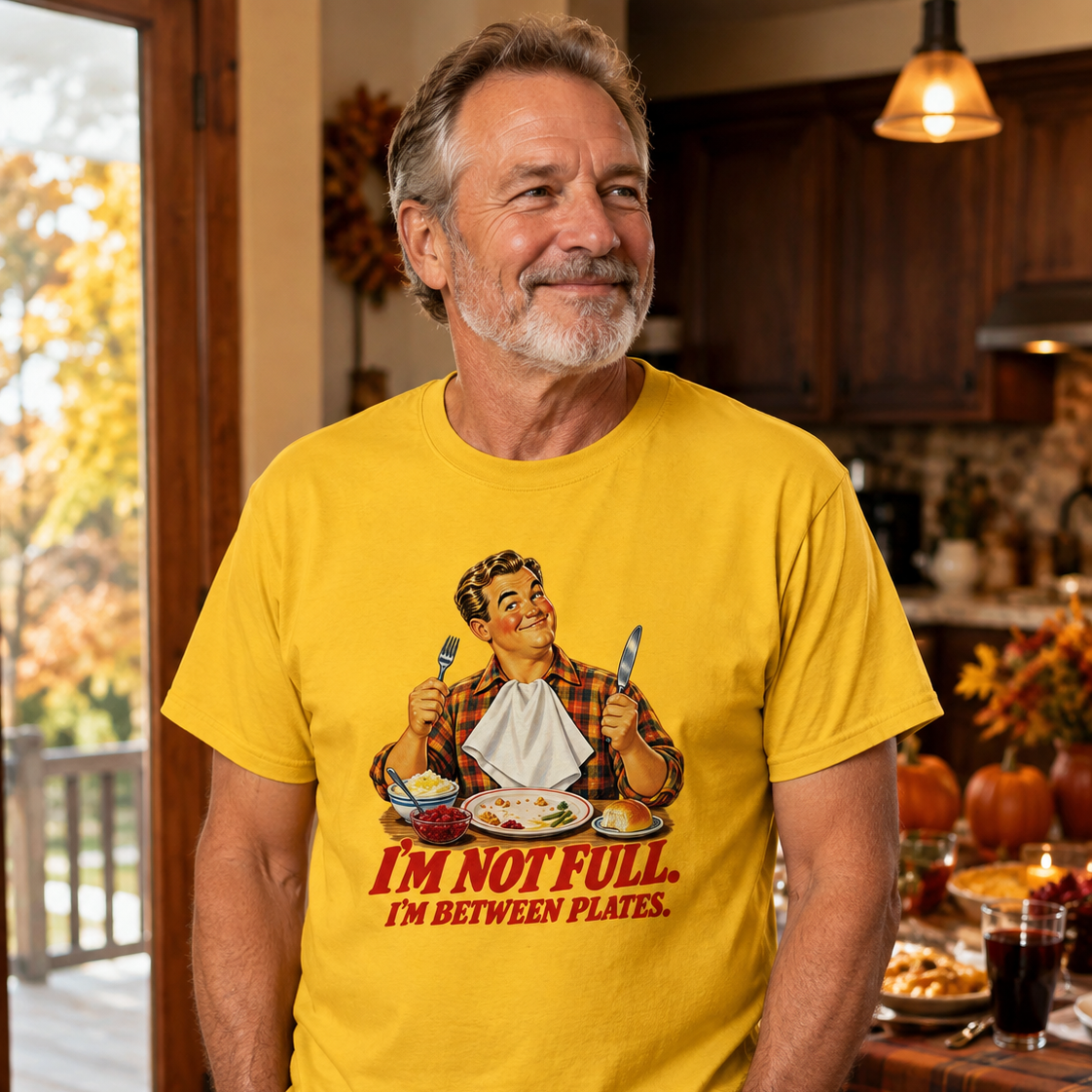 A man wearing a bright yellow graphic t-shirt with a retro illustration and the text 'I'M NOT FULL. I'M BETWEEN PLATES.